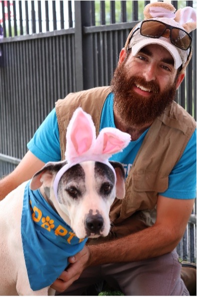 A bearded man, Nic, sits with a dog wearing bunny ears