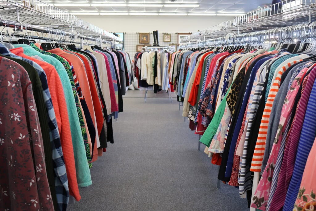 Thrift store clothing racks with colorful garments displayed.